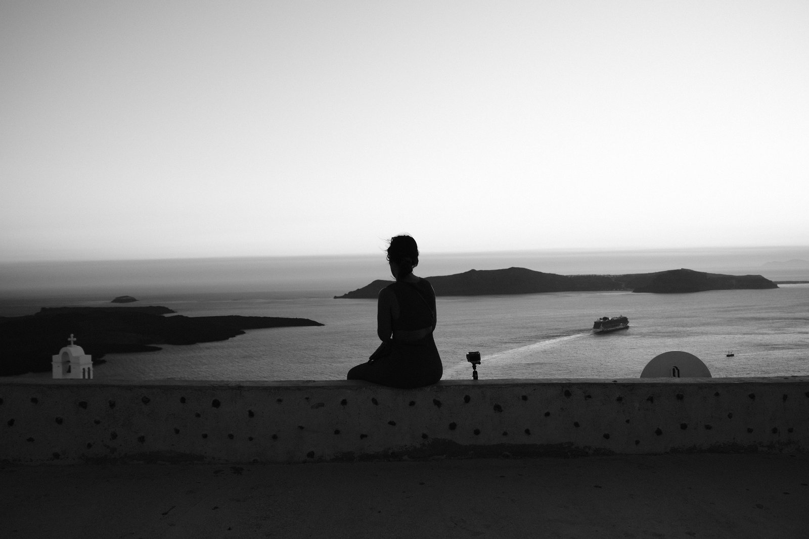 Silueta sentada frente al mar al atardecer, en blanco y negro
