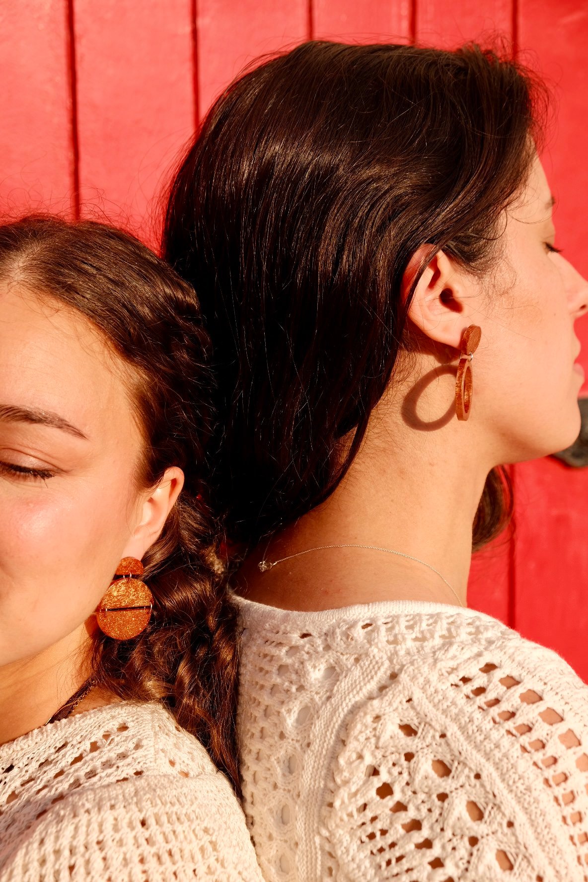 Hibiscus Amarillo: dos chicas con pendientes artesanales sobre fondo rojo