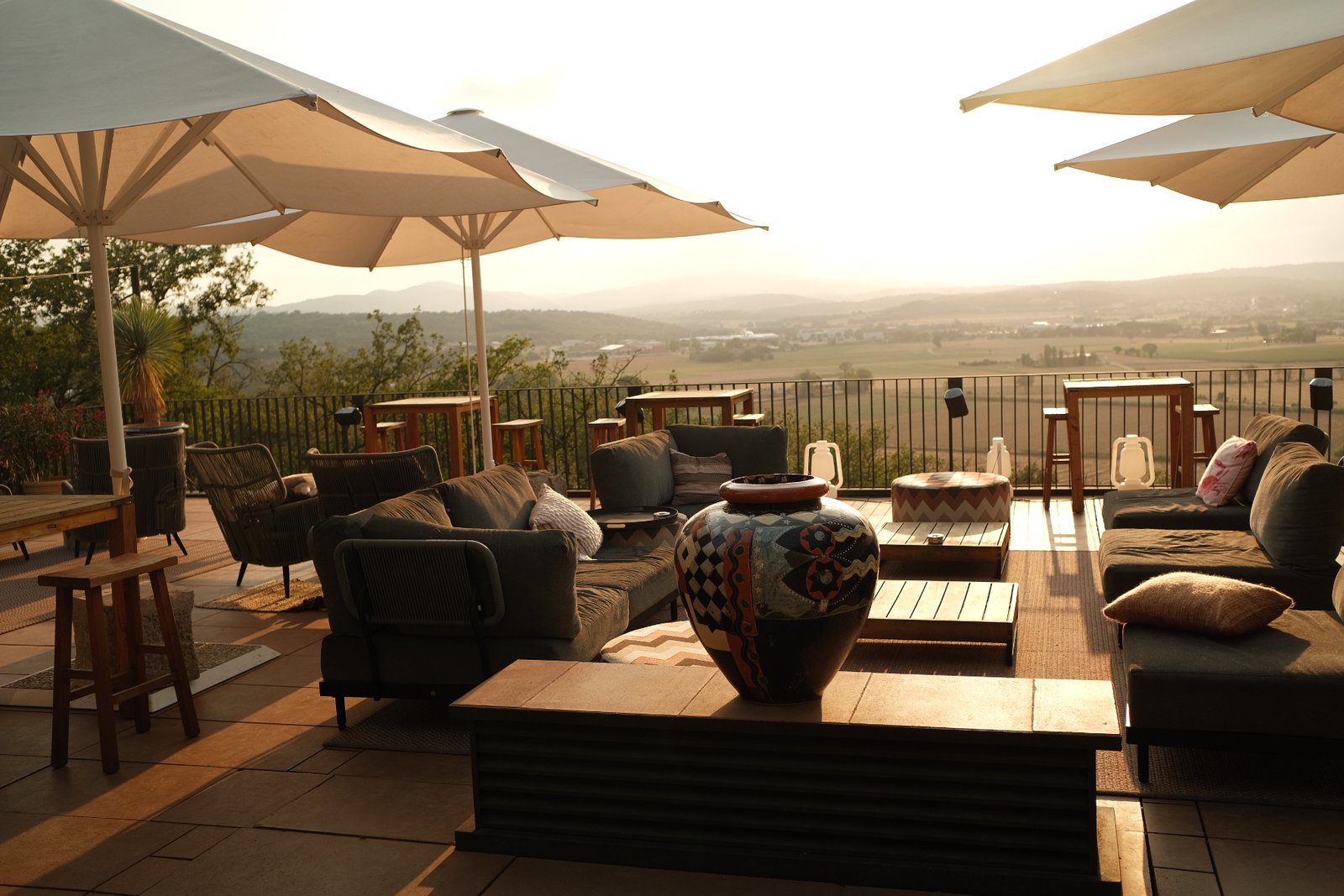 Terraza con sofás y sombrillas al atardecer frente al valle