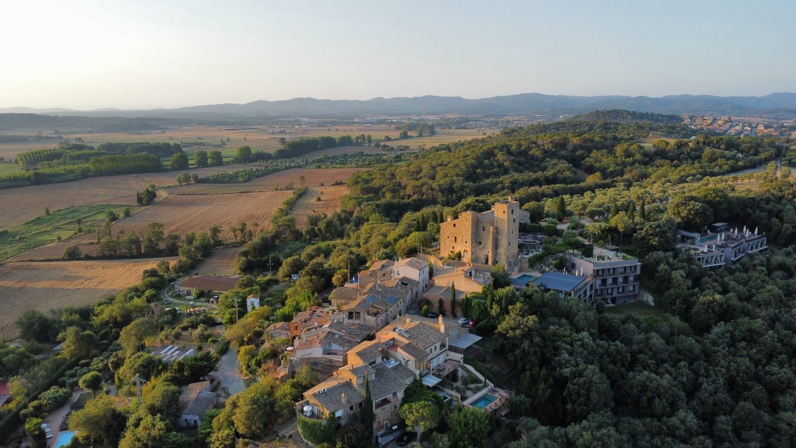 Pueblo de piedra sobre una colina entre bosques, vista aérea con dron