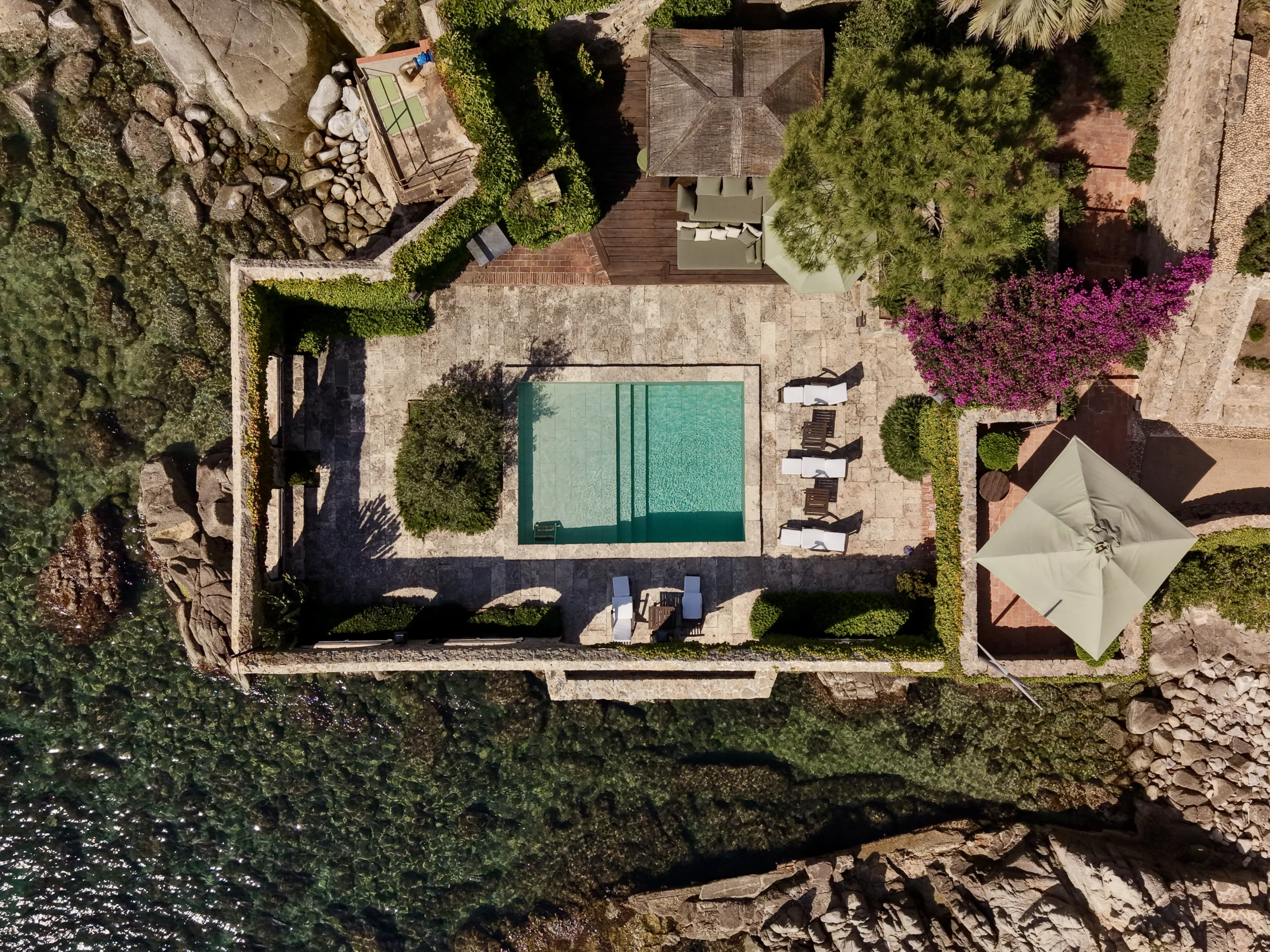 Piscina entre muros de piedra junto al mar, vista aérea con dron